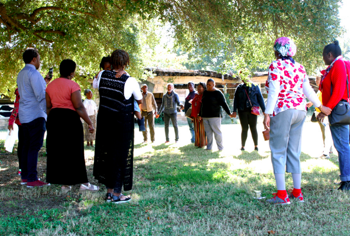 Community members gather in a circle under a tree at M.M. Tate High School, the former Black school in Marvell, to close the listening party. Brenda Hughes lifts song.